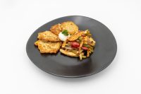Slovak Meat Sauté Mäsové Soté with peppers, sour cream and parsley on a black plate.